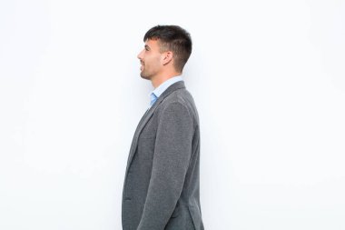 Profil görünümlü genç yakışıklı, beyaz duvara karşı uzayı kopyalamaya çalışıyor, düşünüyor, hayal ediyor ya da hayal kuruyor.