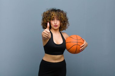 Genç, güzel bir spor kadını basketbol topuyla spor kıyafetleri giyiyor.