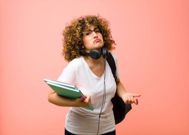 Genç, güzel bir bayan öğrenci, hiçbir fikri olmadan, cahil ve kafası karışık hissediyor. Pembe duvara bakan aptal ya da aptal bir bakışla tamamen şaşkına dönmüş.