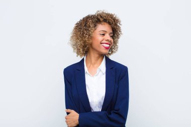 Genç Afro-Amerikan kadını mutlu, neşeli ve kendinden emin görünüyor gururla gülümsüyor ve iki elini de düz duvara dayayıp kalçalarını kaldırmaya çalışıyor.