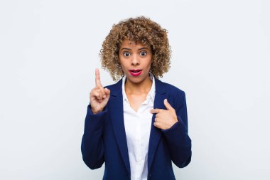 Afrikalı genç bir kadın gururlu ve şaşırmış, kendine güvenen, düz duvara karşı bir numara gibi hisseden