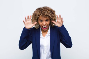 Genç Afro-Amerikalı kadın panik ya da öfke içinde bağırıyor, şok olmuş, korkmuş ya da öfkeli, elleri düz duvara dayalı.