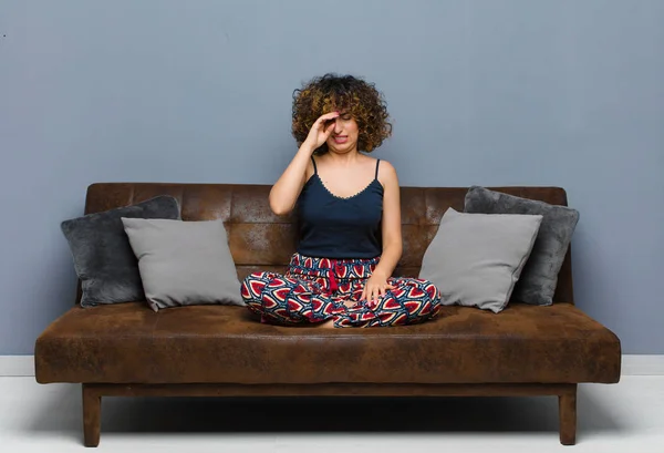 ストレスや疲れや不満を感じ額から汗をかき絶望や疲れを感じソファに座っている若い女性 — ストック写真