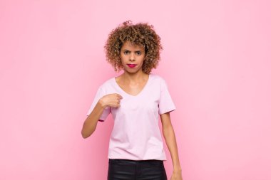 Genç afro-amerikan kadın şaşkın, şaşkın ve güvensiz hissediyor, kendini merak edip bana mı soruyor? Pembe duvara yaslan