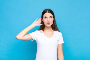 Genç, güzel bir kadın gülümsüyor, tuhaf bir şekilde yan tarafa bakıyor, dedikoduları dinlemeye çalışıyor ya da mavi duvara karşı bir sırrı duymaya çalışıyor.