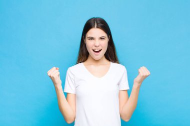 Genç ve güzel bir kadın öfkeli bir ifadeyle ya da mavi duvara karşı başarıyı kutlayan yumruklarla agresif bir şekilde bağırıyor.