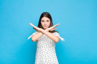 Genç ve güzel bir kadın senin bu tavırlarından rahatsız ve bıkkın görünüyor. Yeter artık! Eller önde çapraz, mavi duvara yaslanmanı söylüyor.