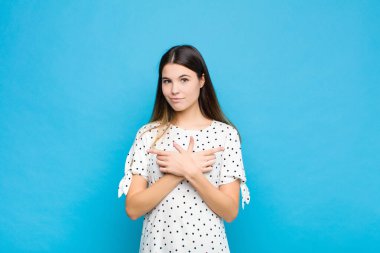Kafası karışık, güvensiz ve mavi duvara karşı şüpheyle zıt yönlere bakan genç ve güzel bir kadın.