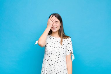 Genç ve güzel bir kadın gülüyor ve alnına şaplak atıyor. Unutmuşum yoksa mavi duvara karşı yaptığım aptalca bir hataydı. 