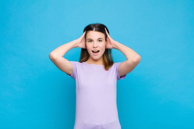 Genç ve güzel bir kadın el ele tutuşuyor, ağzı açık, son derece şanslı, şaşkın, heyecanlı ve mutlu hissediyor.