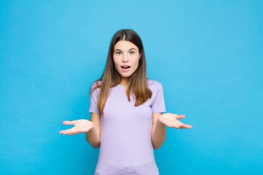 Genç ve güzel bir kadın son derece şaşırmış, endişeli ve paniklemiş hissediyor. Stresli ve dehşete kapılmış bir şekilde mavi duvara bakıyor.
