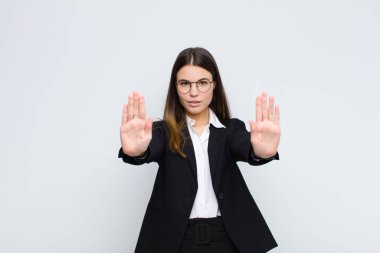Genç iş kadını ciddi, mutsuz, kızgın ve hoşnutsuz görünüyor. Girmeyi yasaklıyor ya da her iki avuç içi de beyaz duvara yaslıyken dur diyor.
