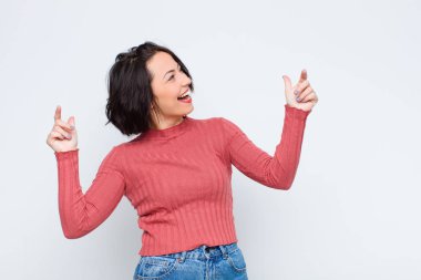 Genç, güzel bir kadın gülümsüyor, tasasız ve mutlu hissediyor, dans ediyor ve müzik dinliyor, beyaz duvarın karşısındaki bir partide eğleniyor.