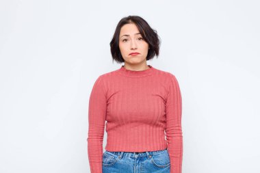 Genç, güzel bir kadın üzgün ve stresli. Kötü bir sürpriz yüzünden üzgün. Olumsuz, endişeli bir bakışla beyaz duvara bakıyor.