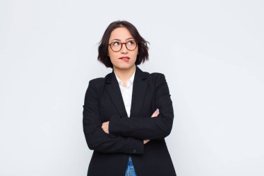 Genç iş kadını kuşkulanıyor ya da düşünüyor, dudağını ısırıyor ve gergin hissediyor, beyaz duvara karşı boşluğu kopyalamak istiyor.