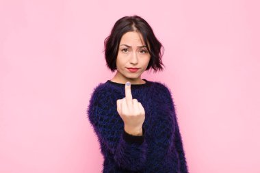 Genç, güzel bir kadın kızgın, sinirli, isyankar ve agresif hissediyor. Orta parmağını sallıyor, pembe duvara karşı savaşıyor.