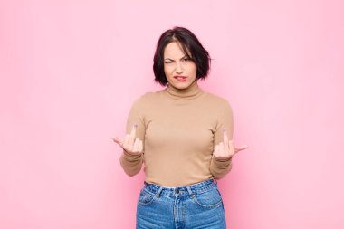 Genç ve güzel bir kadın kışkırtıcı, agresif ve müstehcen hissediyor, pembe duvara karşı isyankar bir tavırla orta parmağını hareket ettiriyor.