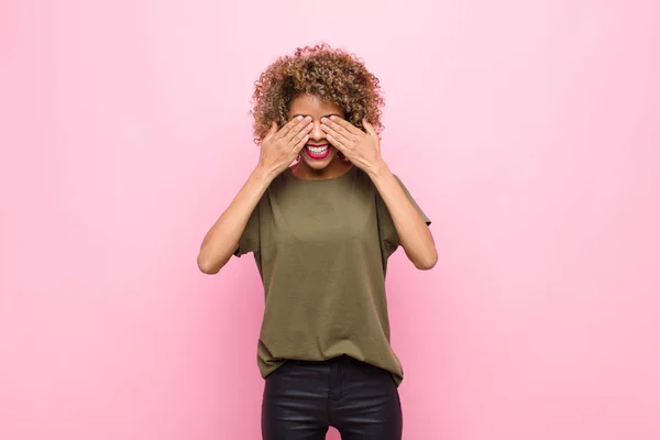 若いアフリカ系アメリカ人の女性は手で目を覆いピンクの壁に対する信じられないほどの驚きを待っています — ストック写真