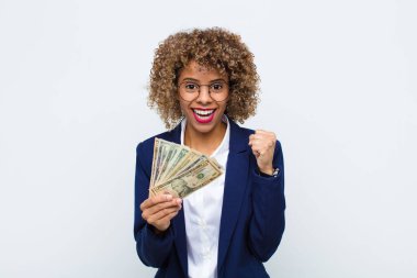 Genç Afrikalı Amerikalı kadın şok olmuş, heyecanlı ve mutlu hissediyor, gülüyor ve başarıyı kutluyor, vay canına! Avro banknotlarıyla