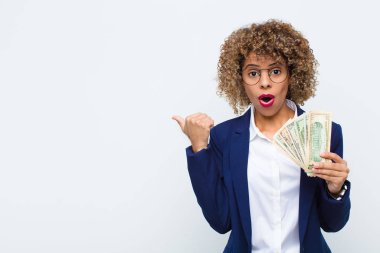 Genç Afrikalı Amerikalı kadın, inanamadığı için hayrete düşmüş, yan taraftaki objeyi işaret ederek, 