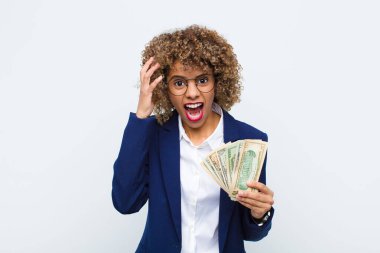 Genç Afrikalı Amerikalı kadın ellerini havaya kaldırıp bağırıyor. Öfkeli, sinirli, stresli ve avro banknotları yüzünden üzgün.