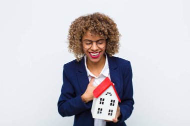 Genç Afrikalı Amerikalı bir kadın komik bir şakaya yüksek sesle gülüyor, mutlu ve neşeli hissediyor, ev modeliyle eğleniyor.