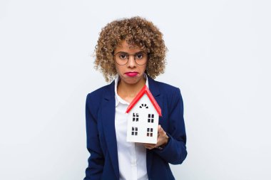 Genç Afrikalı Amerikalı kadın üzgün ve mızmız görünüyor. Mutsuz görünüyor. Ev modeline karşı olumsuz ve hayal kırıklığına uğramış bir tavırla ağlıyor.