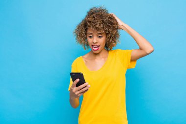 Genç Afro-Amerikan duyguları stresli, endişeli, endişeli ya da korkmuş, elleri başının üstünde, cep telefonuyla yanlışlıkla panikliyor.