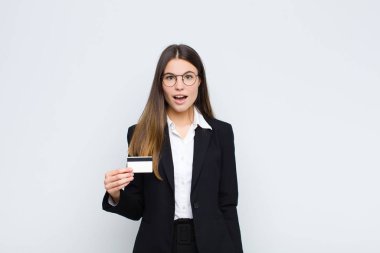 Genç ve güzel bir kadın şok olmuş ya da şaşırmış görünüyor, ağzı açık bir şekilde kredi kartıyla 