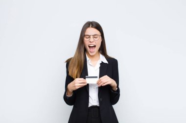 Genç ve güzel bir kadın agresif bir şekilde bağırıyor, kızgın, sinirli, öfkeli ya da sinirli görünüyor, kredi kartıyla hayır diye bağırıyor.