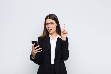 Genç ve güzel bir kadın bir fikri fark ettikten sonra mutlu ve heyecanlı bir dahi gibi hissediyor, neşeli bir şekilde parmağını kaldırıyor, eureka! cep telefonuyla.