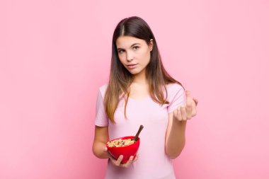 Genç ve güzel bir kadın kızgın, sinirli, isyankar ve agresif hissediyor. Orta parmağını hareket ettiriyor ve bir kahvaltı kasesiyle karşılık veriyor.