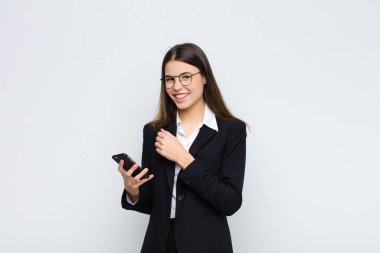Genç, güzel bir kadın mutlu, pozitif ve başarılı hissediyor, bir meydan okumayla karşılaştığında motive oluyor veya iyi sonuçları cep telefonuyla kutluyor.