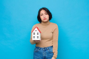 Genç, güzel bir kadın üzgün ve mızmızlanıyor. Mutsuz bir bakışla, negatif ve hayal kırıklığına uğramış bir ev modeliyle ağlıyor.