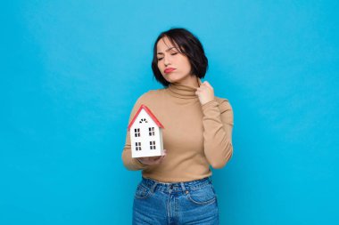 Genç, güzel bir kadın stresli, endişeli, yorgun ve hayal kırıklığına uğramış, gömleğini çekiştiren, bir ev modelinin sorunlarından bıkmış görünüyor.