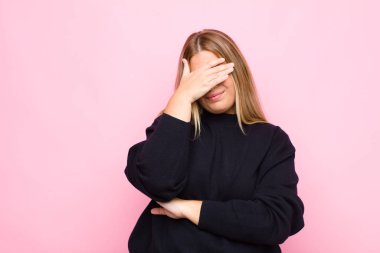 Genç sarışın kadın stresli, utanmış ya da üzgün görünüyordu. Başı ağrıyordu. Yüzü düz duvara dönmüştü.