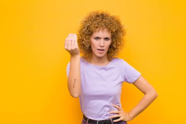 Genç afro kadın sana borcunu ödemeni söyleyerek kapiş ya da para hareketi yapıyor! turuncu duvara yaslan