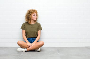 Profil görüntüsü olan genç afro kadın bir yerde oturmuş hayal kuruyor, düşünüyor ve hayal kuruyor.