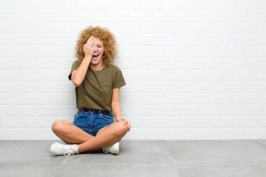 Genç afro kadın gülüyor ve alnına şaplak atıyor. Unutmuşum yoksa yerde oturmak aptalca bir hataydı. 