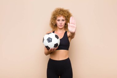 Genç afro kadın ciddi, sert, hoşnutsuz ve kızgın görünüyor. Avuç içini açıp jest sporu kavramını durduruyor.