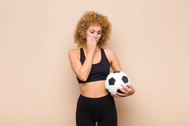 Genç afro kadın ciddi, düşünceli ve endişeli, elleri çene sporu kavramına yaslanmış yan bakıyor.