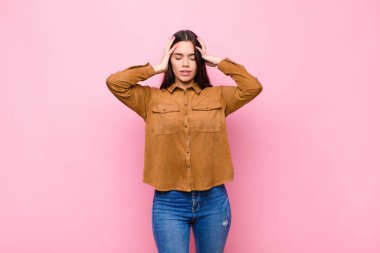 Genç, güzel bir kadın konsantre, düşünceli ve ilham verici görünüyor. Beyin fırtınası yapıyor ve pembe duvarın karşısında elleri alnında hayal ediyor.