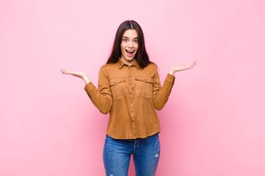 Genç, güzel bir kadın mutlu, heyecanlı, şaşırmış ya da şok olmuş hissediyor. Gülümsüyor ve hayrete düşüyor.