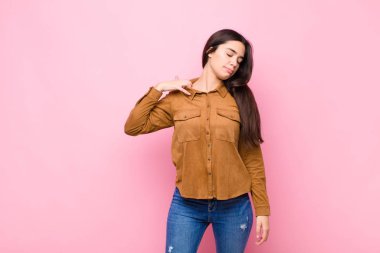 Genç, güzel bir kadın stresli, endişeli, yorgun ve hayal kırıklığına uğramış, gömleğini çekmiş, pembe duvara karşı sorunlu görünüyor.