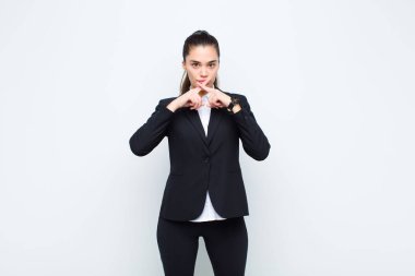 Genç ve güzel bir kadın ciddi ve hoşnutsuz görünüyor. Reddedilmek için iki parmağıyla öne doğru uzanıyor. Sessizlik iş konsepti istiyor.
