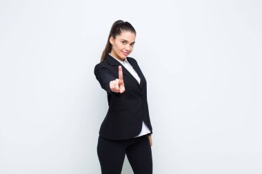 Genç ve güzel bir kadın gururla gülümsüyor ve gururla bir numaralı pozu veriyor. Kendini lider iş konsepti gibi hissediyor.
