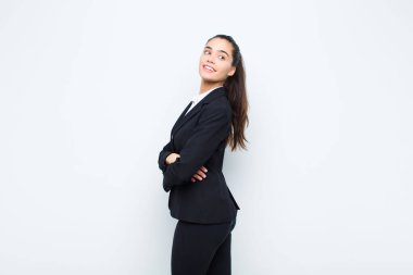Genç, güzel bir kadın neşeyle gülümsüyor, mutlu, tatmin olmuş ve rahatlamış hissediyor, kollarını kavuşturup, yan iş kavramına bakıyor.