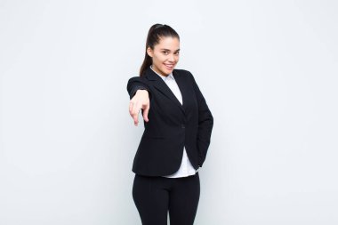 Genç ve güzel bir kadın kameraya bakıyor. Tatmin olmuş, kendine güvenen, dostça gülümseyen, iş konseptini seçen.