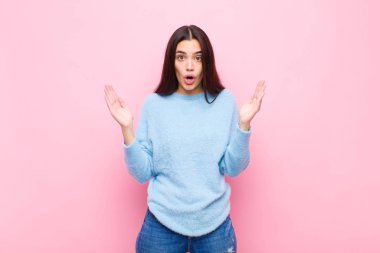 Genç, güzel bir kadın pembe duvara karşı inanılmaz bir şey fark edince şaşırmış ve şaşırmış görünüyor.