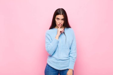 Genç ve güzel bir kadın sessizlik ve sessizlik istiyor, parmaklarıyla ağzının önünde işaret ediyor, 